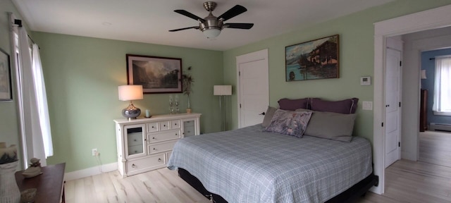 bedroom featuring light wood finished floors, a ceiling fan, and baseboards