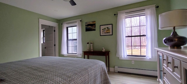 bedroom featuring a baseboard radiator, a ceiling fan, and light wood-style floors
