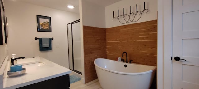 full bathroom with vanity, wood walls, a freestanding tub, and a stall shower