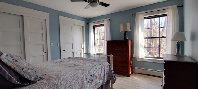 bedroom featuring a baseboard heating unit, light wood-type flooring, and ceiling fan