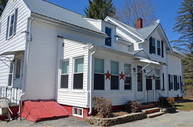 view of side of property featuring a chimney and metal roof
