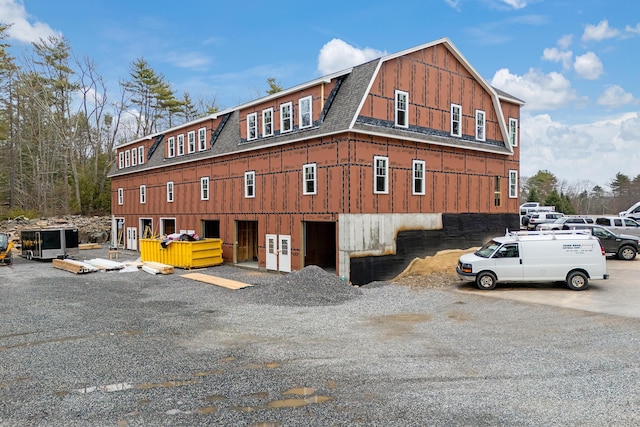 view of side of home featuring a gambrel roof and roof with shingles