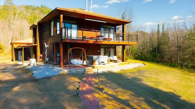 back of property featuring a patio area, a forest view, a hot tub, and a deck