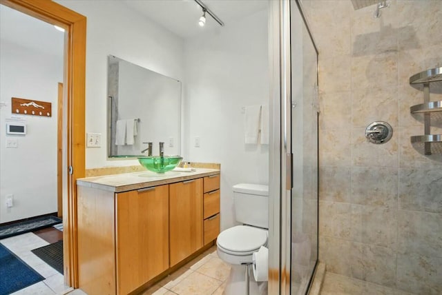 full bathroom with a shower stall, tile patterned floors, vanity, track lighting, and toilet