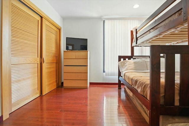 bedroom with recessed lighting, wood finished floors, a closet, and baseboards