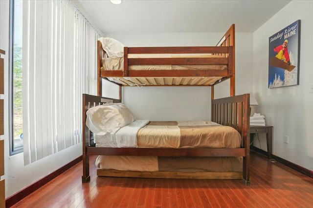 bedroom with multiple windows, baseboards, and wood-type flooring