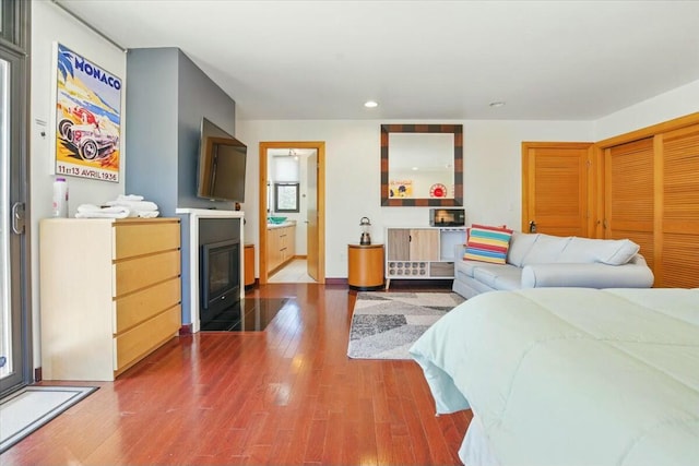 bedroom featuring a fireplace with flush hearth, wood finished floors, and recessed lighting