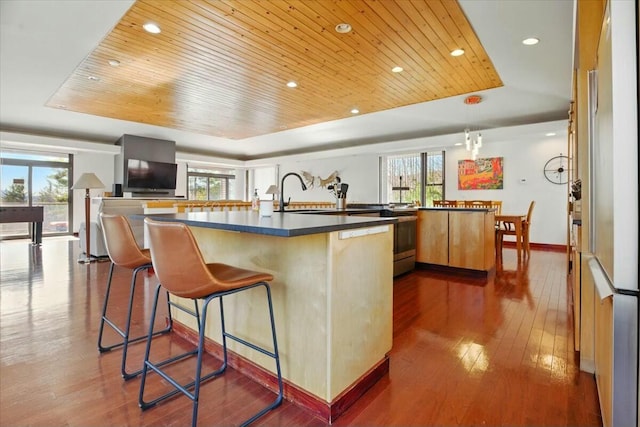 kitchen with dark countertops, wooden ceiling, a wealth of natural light, and a raised ceiling