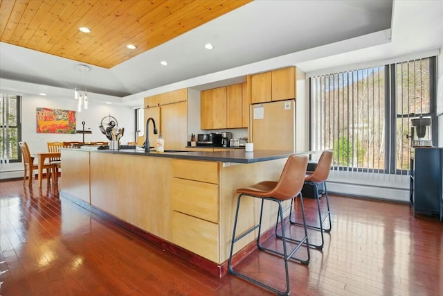 kitchen featuring a baseboard radiator, dark countertops, refrigerator, and dark wood-style floors