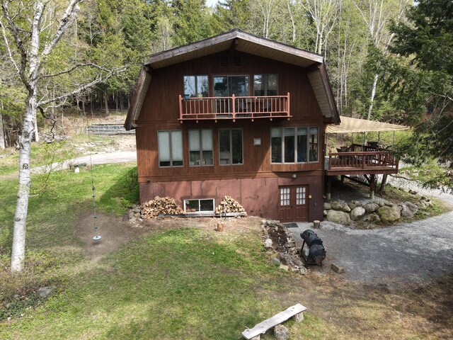 823 Grindstone Rd, Medway, ME 04460 - rustic home with a balcony, a view of trees, a front lawn, and a wooden deck