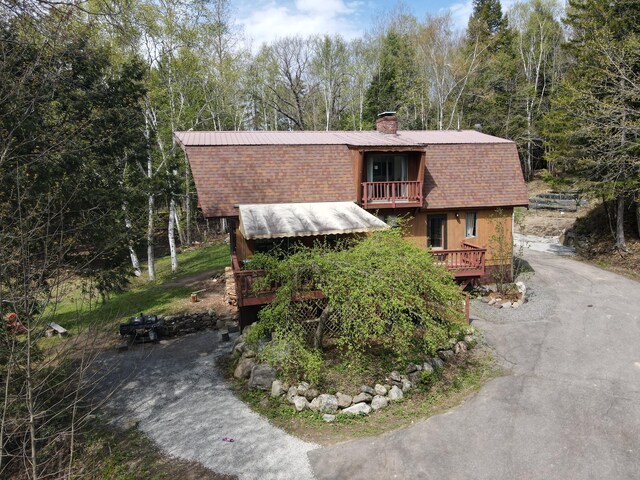 823 Grindstone Rd, Medway, ME 04460 - dutch colonial with a balcony, a chimney, a gambrel roof, asphalt driveway, and a shingled roof