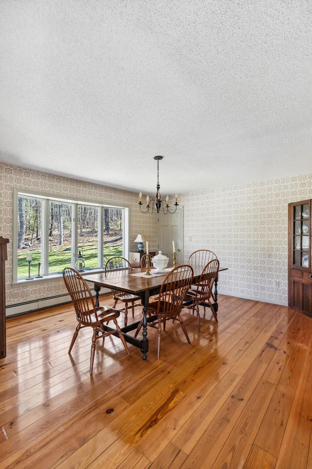 126 Middle Rd, Woolwich, ME 04579 - dining area featuring light wood-style floors, an inviting chandelier, wallpapered walls, and a textured ceiling