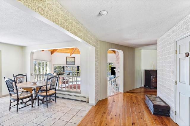 126 Middle Rd, Woolwich, ME 04579 - dining room featuring wood-type flooring, arched walkways, a textured ceiling, wallpapered walls, and a baseboard radiator