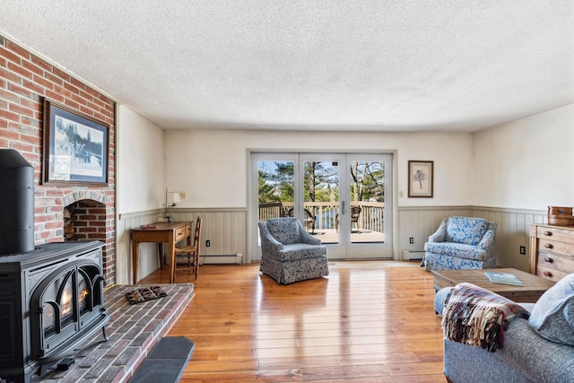 126 Middle Rd, Woolwich, ME 04579 - living room featuring a wood stove, wainscoting, baseboard heating, and hardwood / wood-style floors