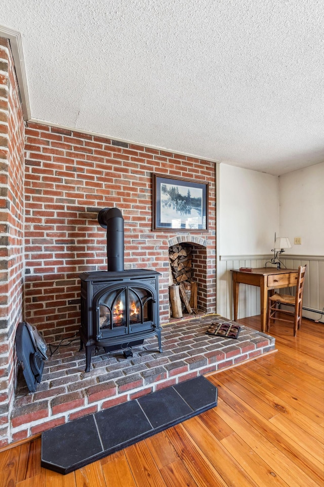 126 Middle Rd, Woolwich, ME 04579 - room details featuring a textured ceiling, wood finished floors, a wood stove, and a wainscoted wall