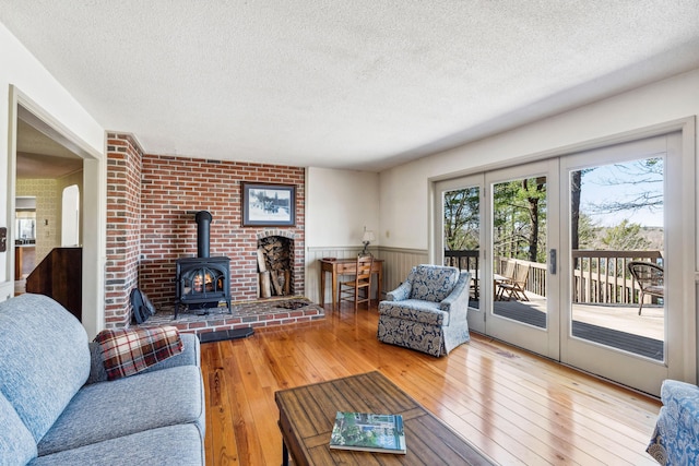 126 Middle Rd, Woolwich, ME 04579 - living area featuring a wainscoted wall, wood-type flooring, a wood stove, and a textured ceiling