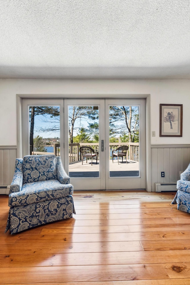 126 Middle Rd, Woolwich, ME 04579 - sitting room featuring french doors, a baseboard radiator, a textured ceiling, and a wainscoted wall