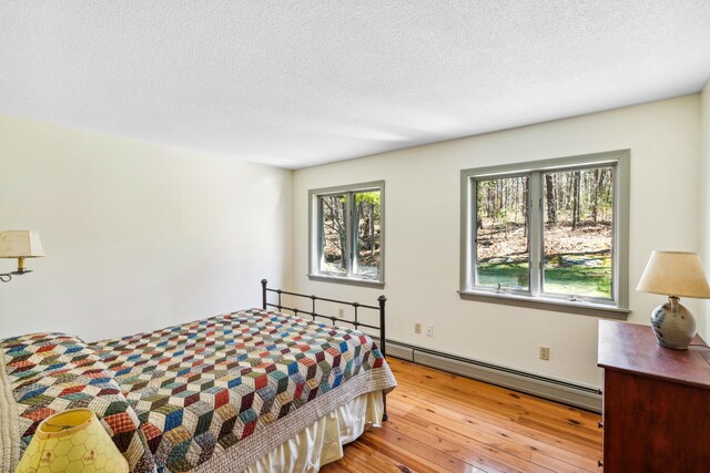 126 Middle Rd, Woolwich, ME 04579 - bedroom featuring a textured ceiling, baseboard heating, and light wood-style floors