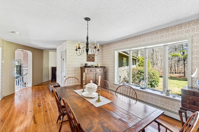 126 Middle Rd, Woolwich, ME 04579 - dining room featuring wallpapered walls, a textured ceiling, arched walkways, light wood finished floors, and a notable chandelier