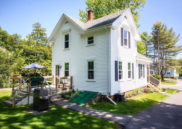 22 Mills Rd, Newcastle, ME 04553 - view of home's exterior with a chimney, a wooden deck, a lawn, and a shingled roof