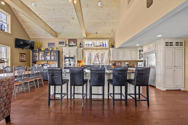 kitchen with dark countertops, appliances with stainless steel finishes, wooden ceiling, high vaulted ceiling, and glass insert cabinets