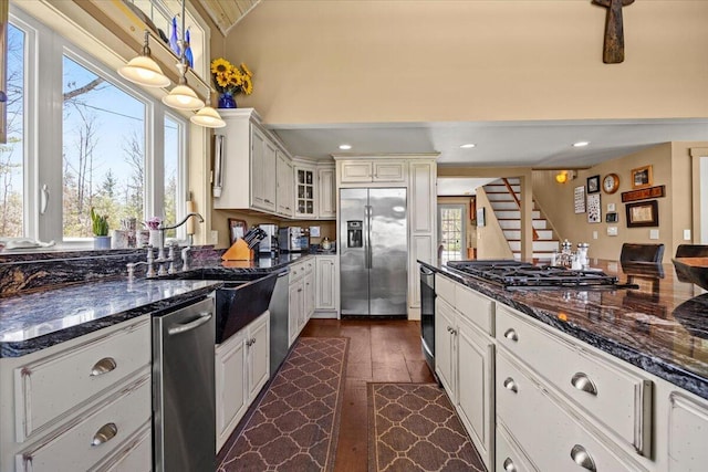 kitchen featuring appliances with stainless steel finishes, a sink, dark wood finished floors, lofted ceiling, and glass insert cabinets