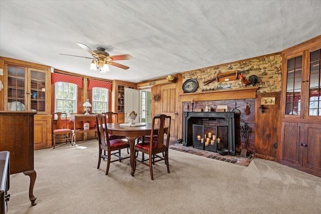 carpeted dining space with a fireplace with flush hearth and ceiling fan