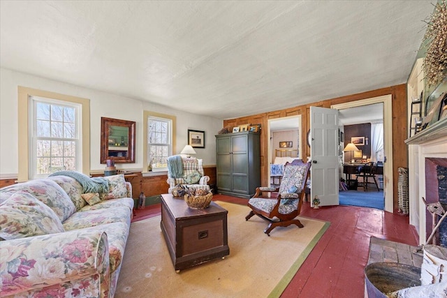 living area with a fireplace with flush hearth, wooden walls, and hardwood / wood-style floors