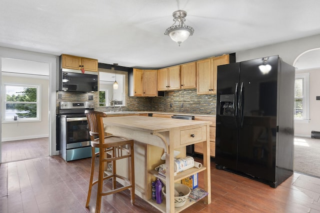 kitchen with decorative backsplash, black fridge with ice dispenser, stainless steel range with electric cooktop, and butcher block counters
