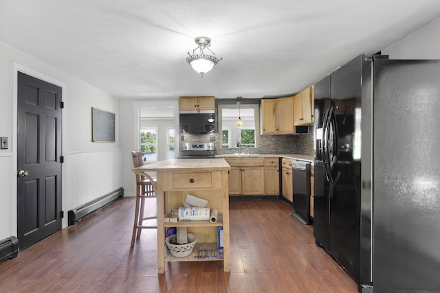 kitchen with decorative backsplash, appliances with stainless steel finishes, a baseboard heating unit, light brown cabinetry, and dark wood finished floors