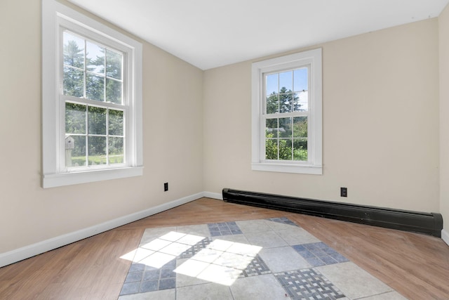 unfurnished room featuring baseboards, wood finished floors, and a baseboard heating unit