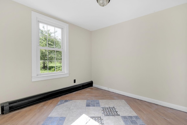 spare room featuring wood finished floors, baseboard heating, and baseboards