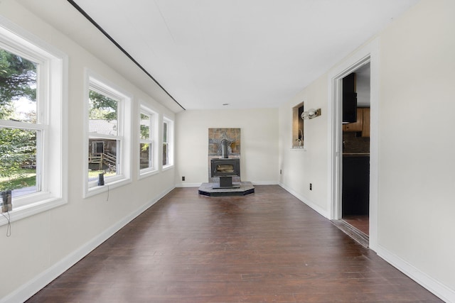 unfurnished sunroom featuring a wood stove and a healthy amount of sunlight