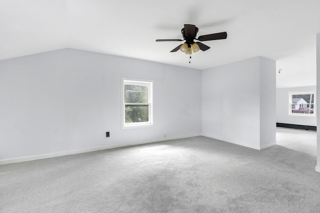 carpeted empty room with ceiling fan, vaulted ceiling, and baseboards