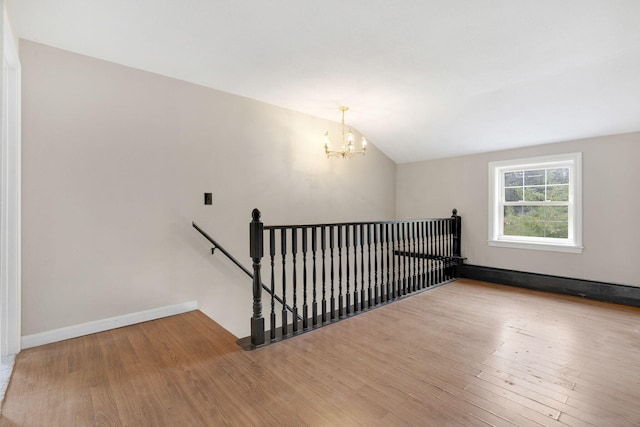 interior space featuring a chandelier, baseboards, wood finished floors, and lofted ceiling