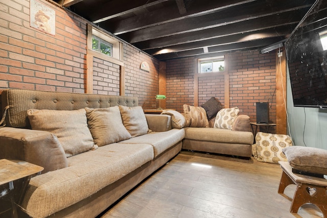 living room with hardwood / wood-style floors, brick wall, and plenty of natural light