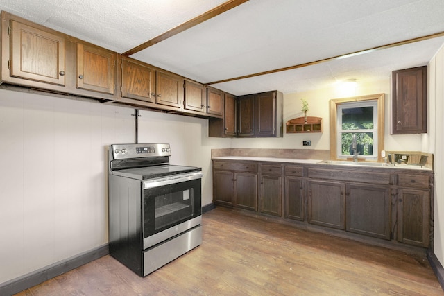 kitchen featuring light wood-style flooring, a sink, dark brown cabinets, baseboards, and electric range