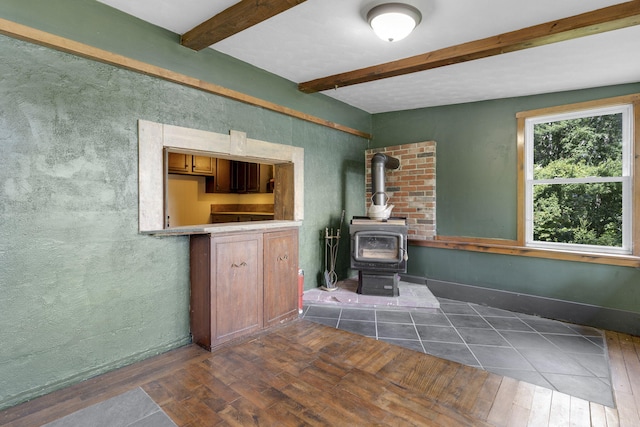 living room featuring a wood stove, beamed ceiling, and dark wood-style flooring