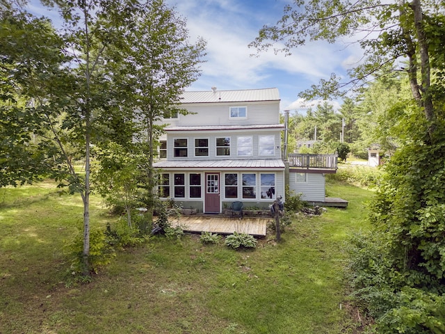 back of property with metal roof, a wooden deck, and a yard