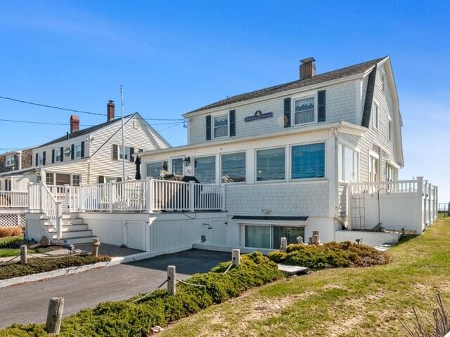 rear view of property with a deck, a gambrel roof, and a chimney