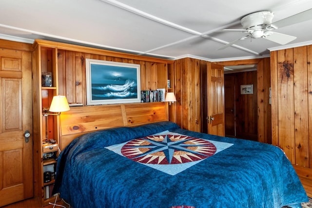 bedroom with ceiling fan and wooden walls