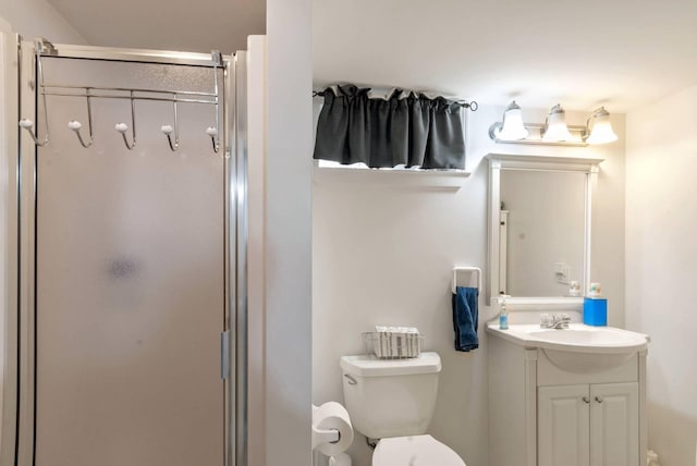 bathroom with toilet, vanity, and a shower stall