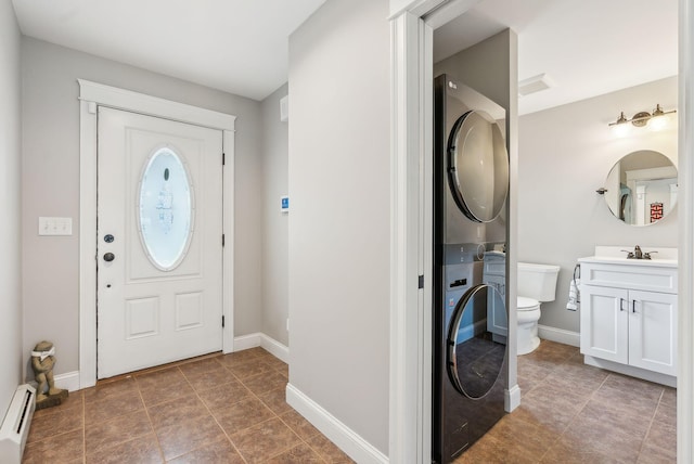 foyer entrance with stacked washer / dryer, tile patterned floors, baseboards, and baseboard heating