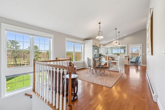 dining space featuring a baseboard heating unit, plenty of natural light, and lofted ceiling