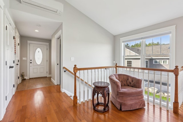 foyer featuring baseboards, an AC wall unit, high vaulted ceiling, and light wood-style flooring