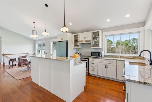 kitchen with a sink, stainless steel appliances, a wealth of natural light, under cabinet range hood, and a kitchen island