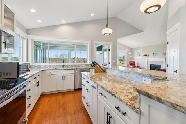 kitchen featuring a sink, white cabinets, stainless steel appliances, and lofted ceiling