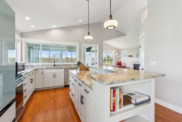 kitchen featuring stainless steel dishwasher, light stone countertops, a sink, and lofted ceiling