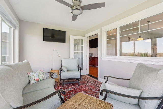 living area with ceiling fan, plenty of natural light, and wood finished floors
