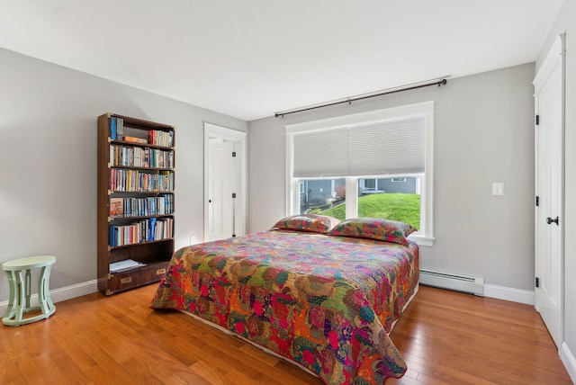 bedroom featuring baseboards, wood finished floors, and a baseboard radiator